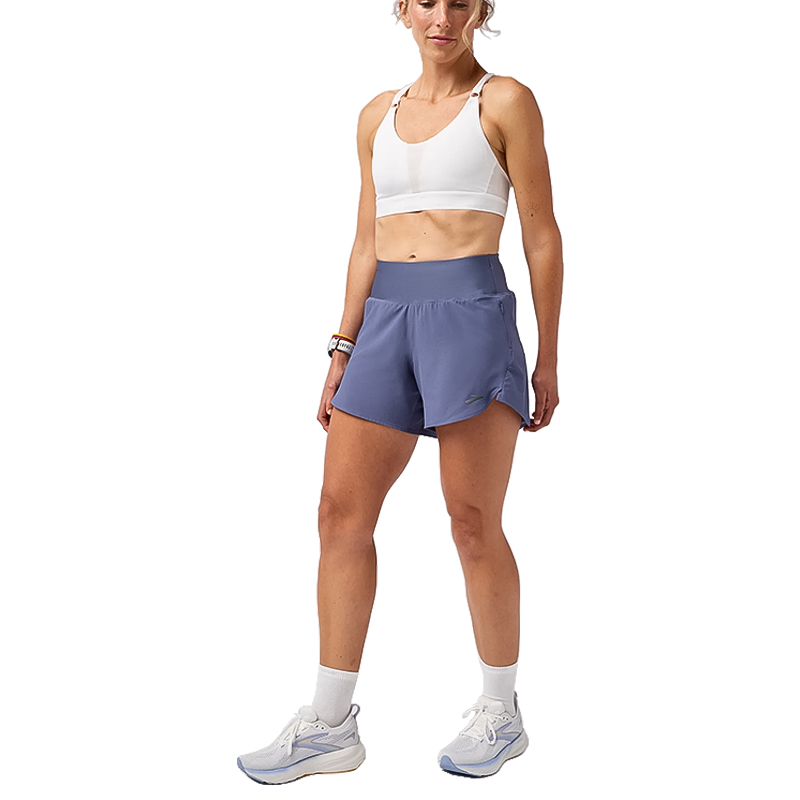 A woman in blue shorts and a white sports bra, showcasing lightweight running gear.