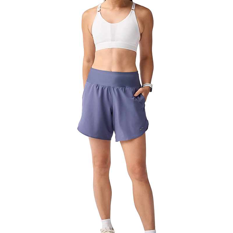 Woman in a sports bra and blue Brooks 7" shorts, showing a comfortable running outfit.