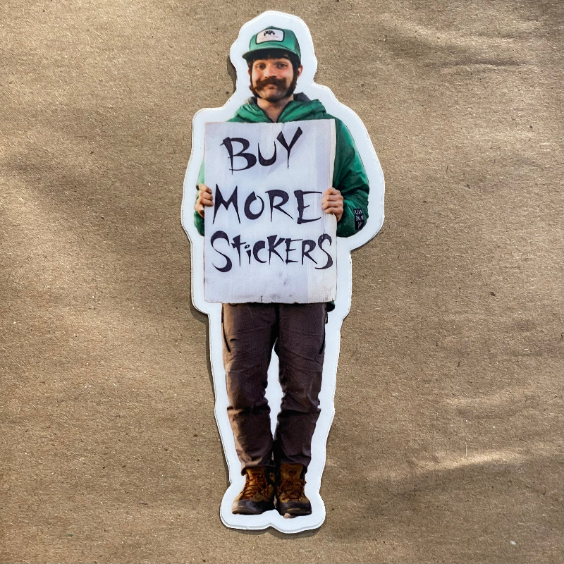 man holding sign that reads "Buy More Stickers"