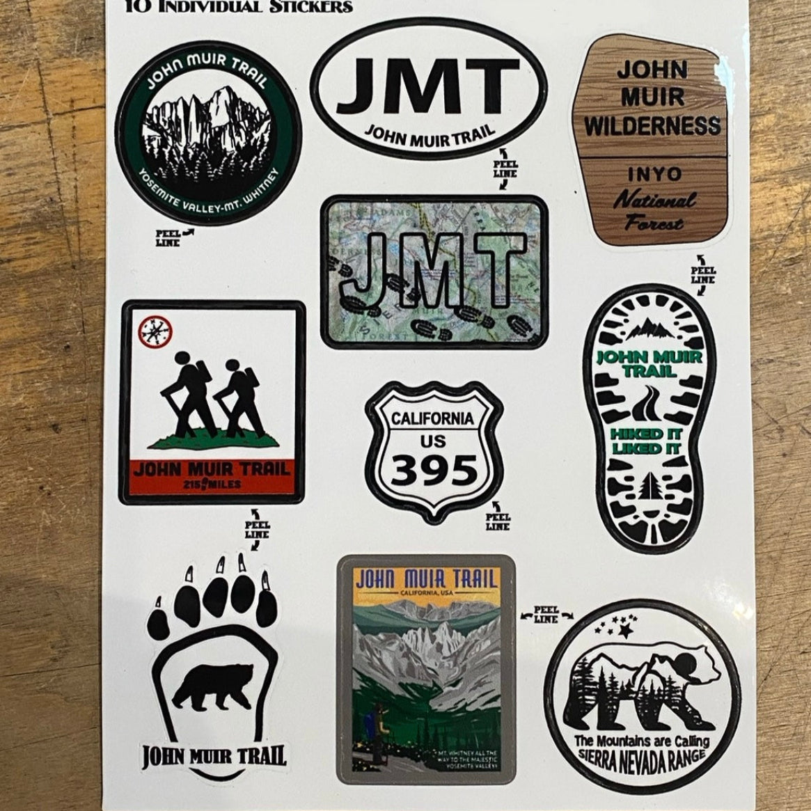 Sheet of 10 individual John Muir Trail stickers on a wooden backrgound