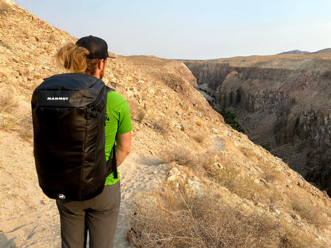 man wearing mammut neon gear 45 liter pack with mountain scape background