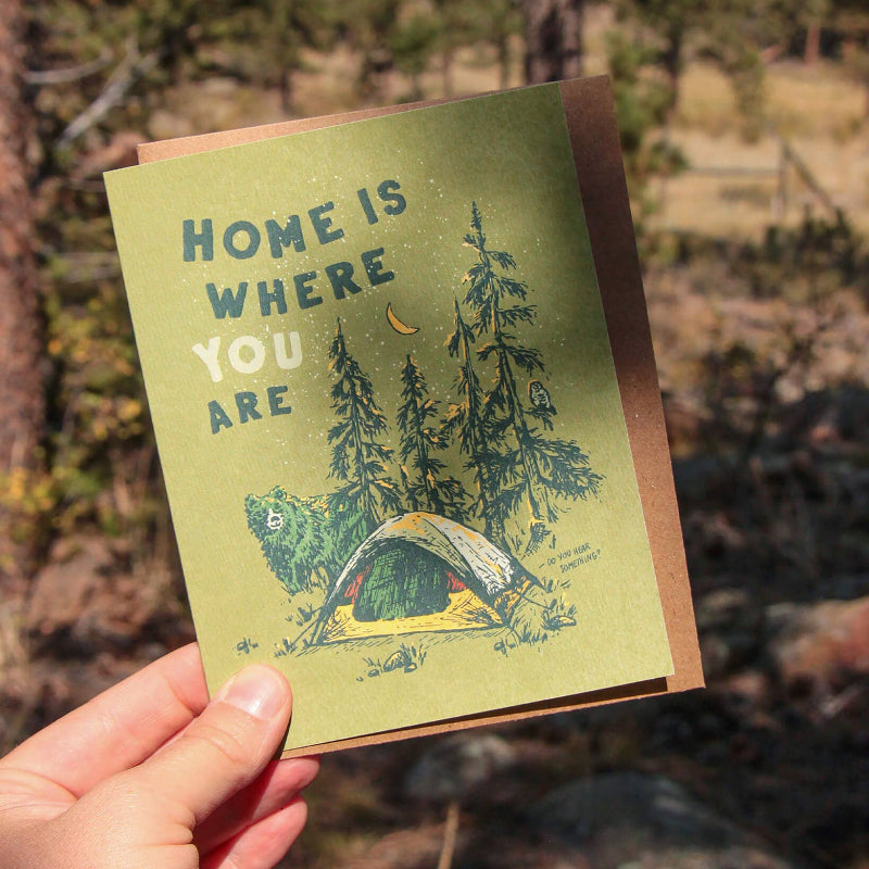 Card reads "Home is where you are," showing a tent in the woods with a bear and owl, celebrating outdoor connections.
