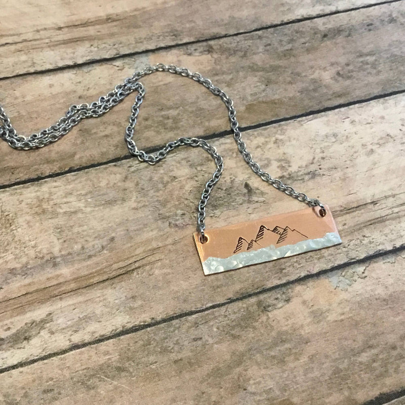 Copper bar necklace featuring a hand-stamped mountain scene, on an 18-inch surgical stainless steel chain.