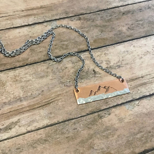 Copper bar necklace featuring a hand-stamped mountain scene, on an 18-inch surgical stainless steel chain.
