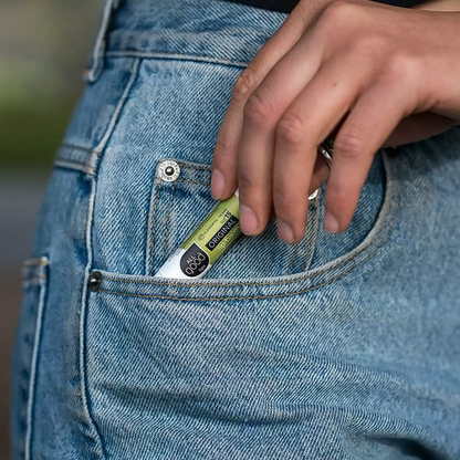 A person holds a small eco-friendly All Good organic original Lips SPF15 lip balm in their pocket.