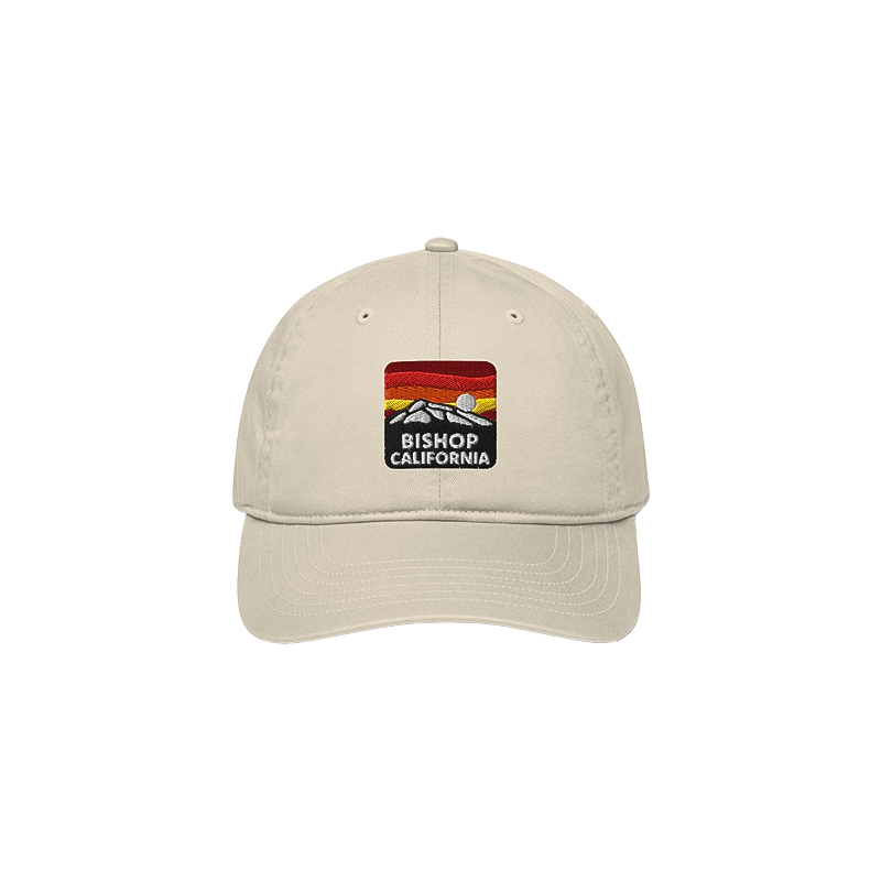 Beige organic baseball cap with a Bishop, California logo, featuring a relaxed fit and adjustable closure for eco-conscious style.