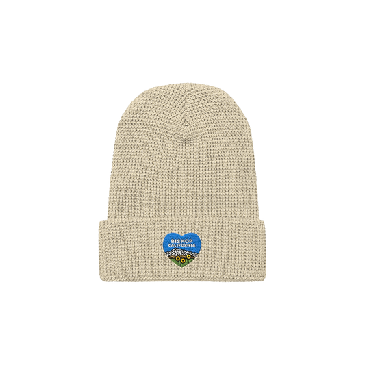 Blue heart design on a beige cozy waffle-knit beanie, perfect for warmth and style in cold weather adventures.