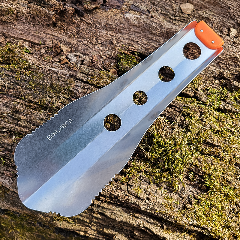 An orange rests on a tree, designed for efficient digging and versatility in outdoor adventures.