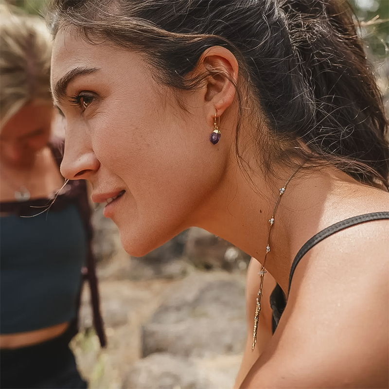 A woman wearing unique rough-cut amethyst gemstone earrings showcasing an artisan-made design.