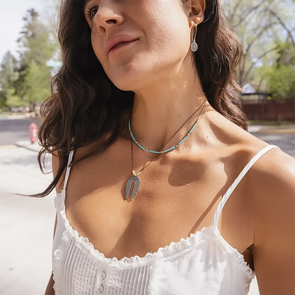 A woman in a white top showcases a Waterfall Necklace with sterling silver pendant and gold vermeil beads.