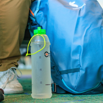 A hiker sitting with a green CNOC 42mm Vesica Collapsible Bottle on the ground, highlighting its compact and collapsible features for easy transport.