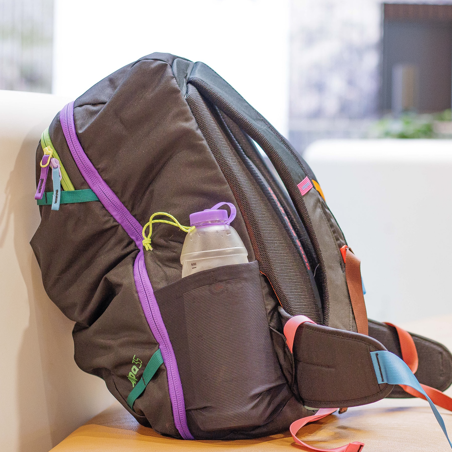 A close-up of a backpack with a purple CNOC 42mm Vesica Collapsible Bottle in its holder, highlighting its convenience for outdoor activities.