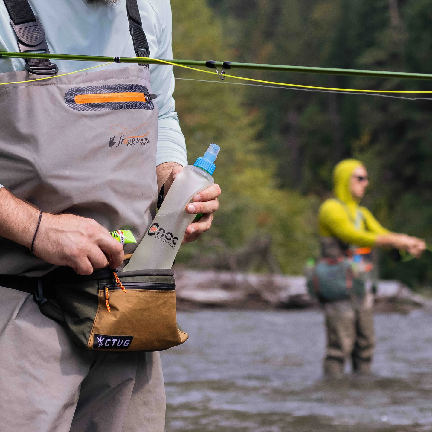 A man holds a water bottle showcasing outdoor hydration while fishing.