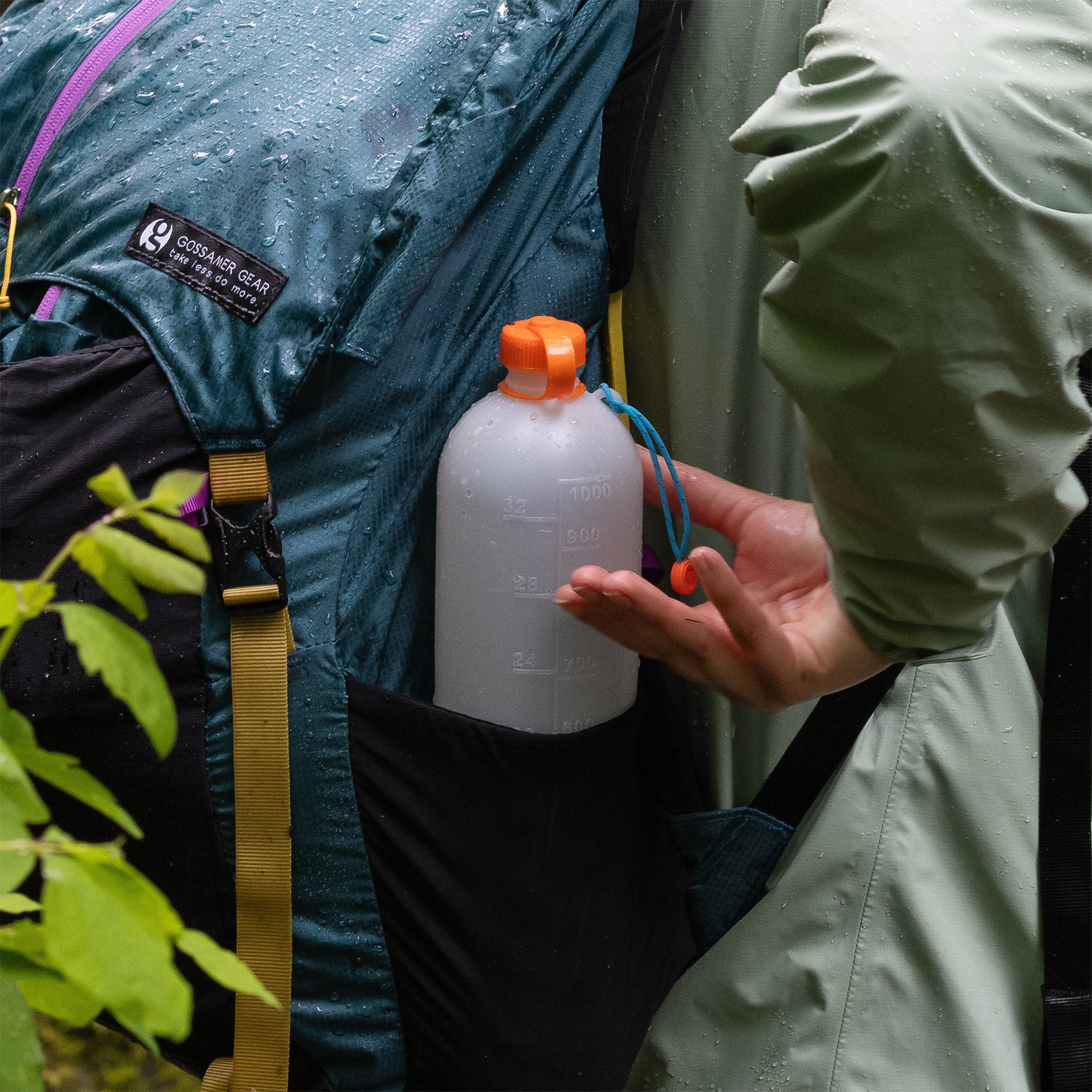 A backpacker trying to reach a lightweight water bottle from her backpack, designed for easy packing and compatible with popular water filters.