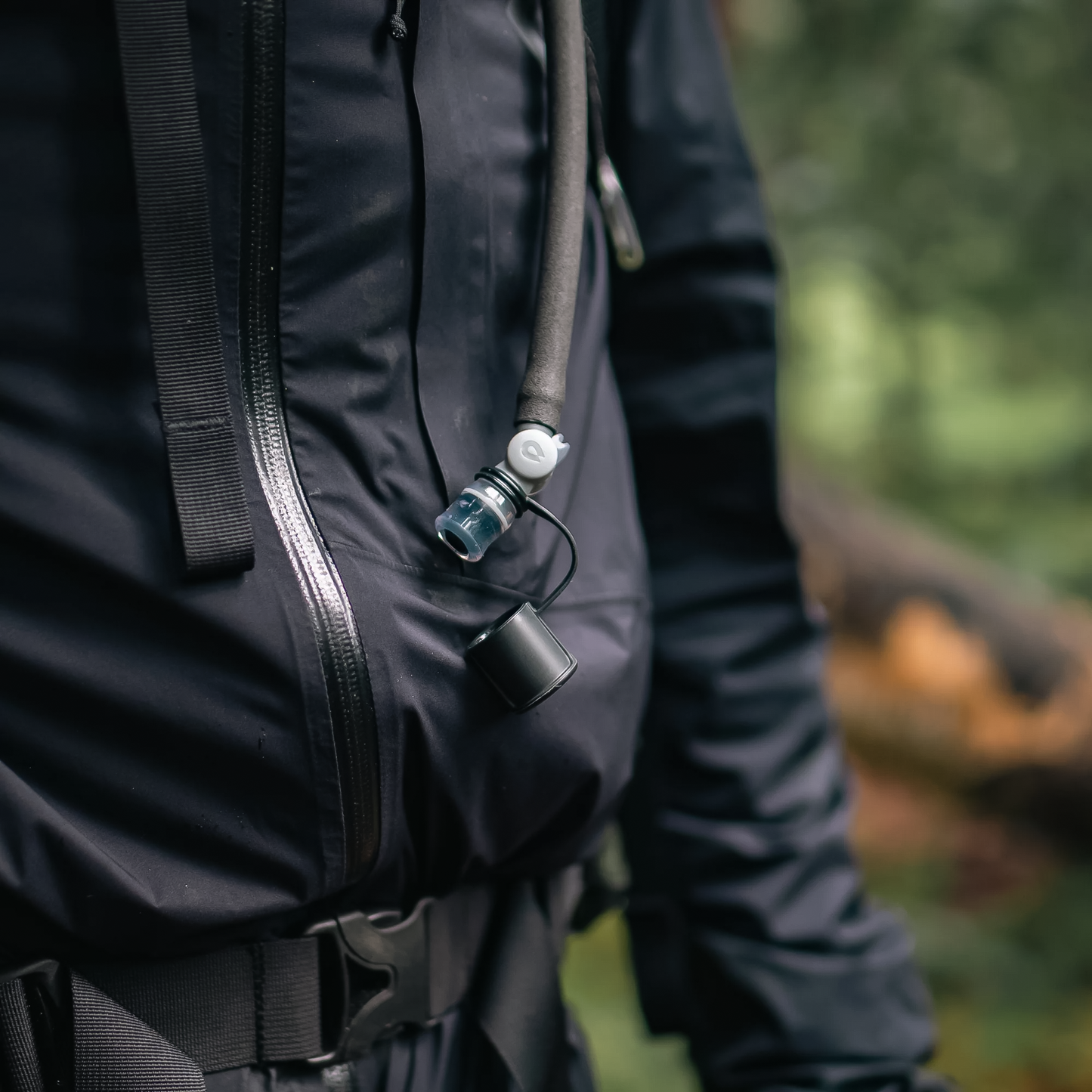 A hiker with a backpack and jacket showcases the HydraPak Force DSL hydration reservoir, ideal for outdoor adventures.