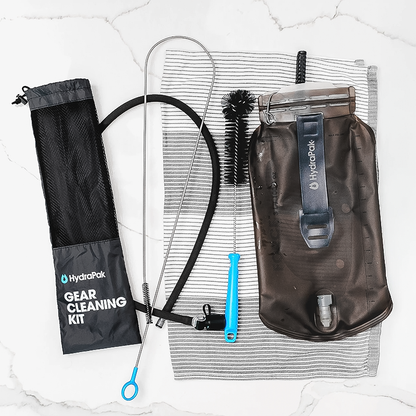 The image shows a water bottle and cleaning brushes neatly packed in a nylon mesh bag, ready for hydration maintenance.