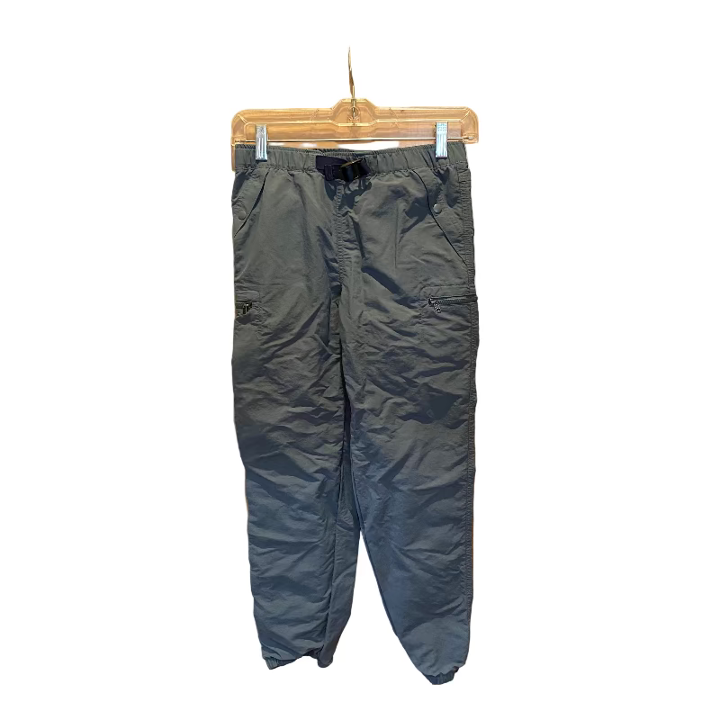 Dark blue pants hanging on a clear hanger against a wooden door.
