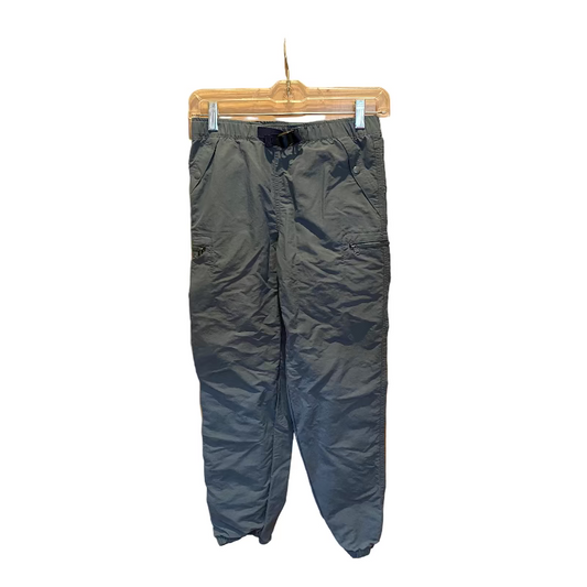 Dark blue pants hanging on a clear hanger against a wooden door.