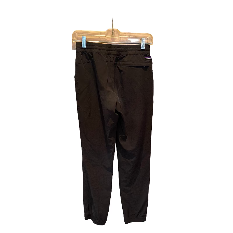 Black pants hanging on a rack against a plain background