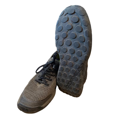 Black hiking boots with textured sole on a wooden floor in a store setting