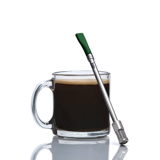 A cup of coffee with a green portable brewing straw for coffee and tea on the side.