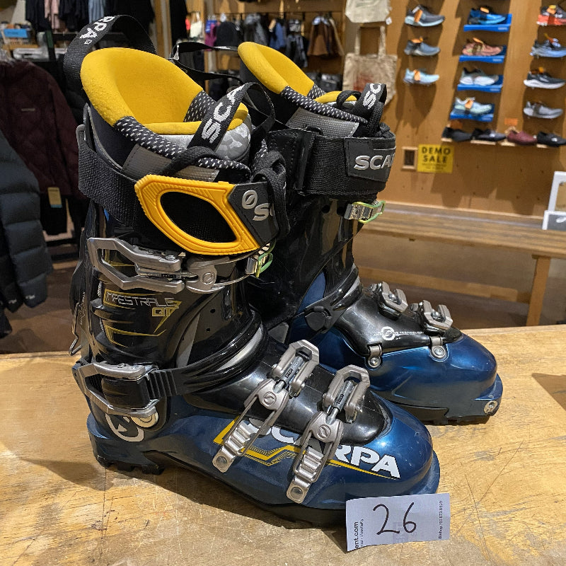 Pair of ski boots with visible brand name on a wooden surface in a store setting.