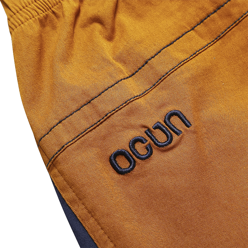 Close-up of the Ocún logo on men's climbing pants in brown, highlighting style and functionality.