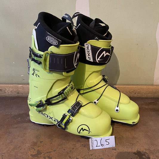 Pair of yellow ski boots with black straps on a brown surface.