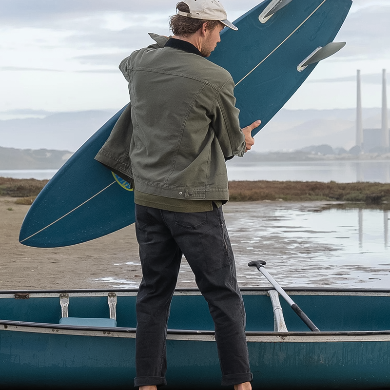 A man stands on a boat, holding a surfboard, ready for a day of surfing on the water.