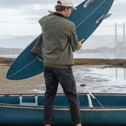 A man stands on a boat, holding a surfboard, ready for a day of surfing on the water.