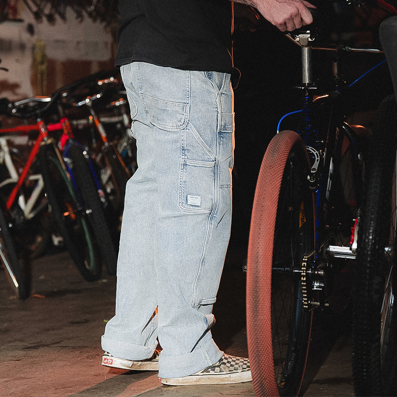 A man stands next to a bike, showcasing his Ripton Men's Utility Jeans, designed for comfort and durability.