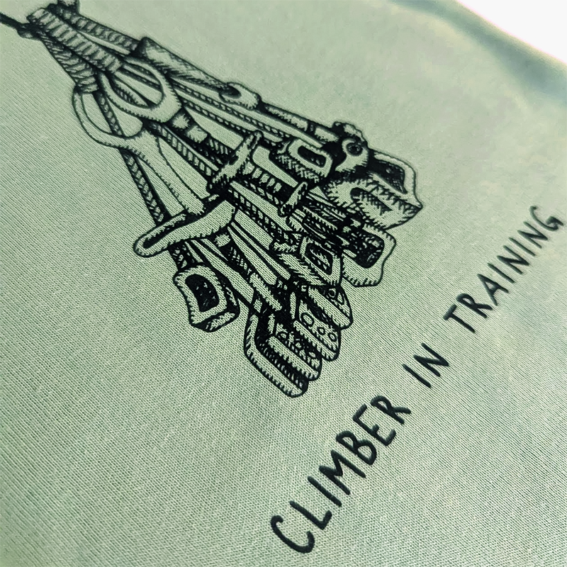 Soft organic cotton green baby bodysuit with a hand-drawn climbing rack and "Climber in Training" slogan, ideal for little adventurers.