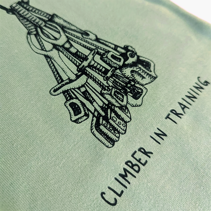 Soft organic cotton green baby bodysuit with a hand-drawn climbing rack and "Climber in Training" slogan, ideal for little adventurers.