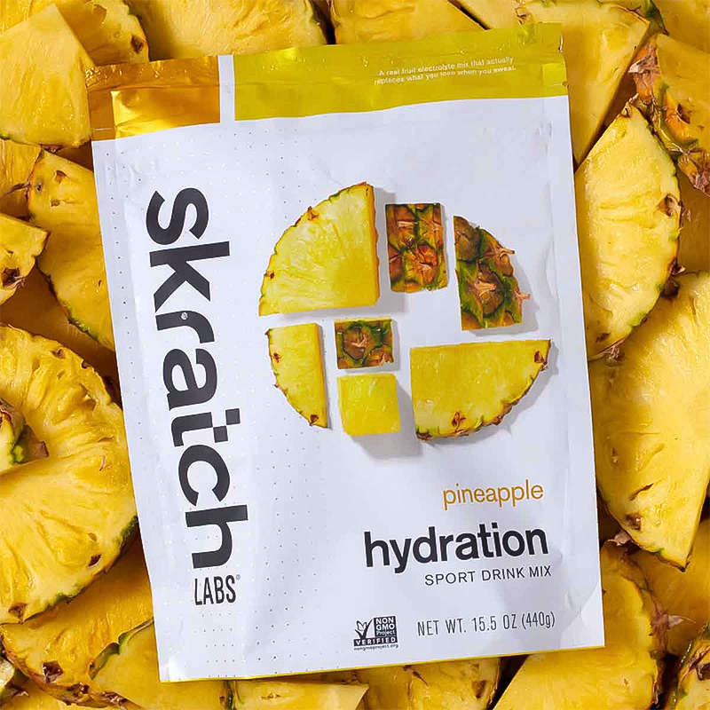Skratch Labs pineapple hydration drink mix packet surrounded by pineapple slices