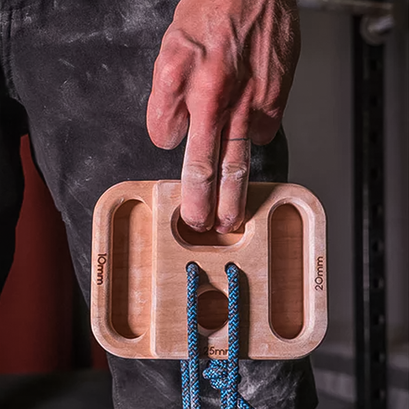 Climber's hand gripping wooden hangboard with blue climbing rope, essential for finger strength training