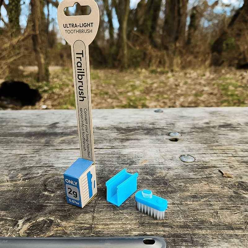A blue toothbrush on a table, featuring the ultralight Trail Stuff Trailbrush. 