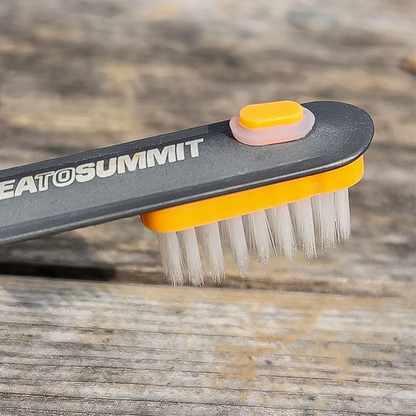 An orange toothbrush designed to attach to long-handled camp utensils for hikers.