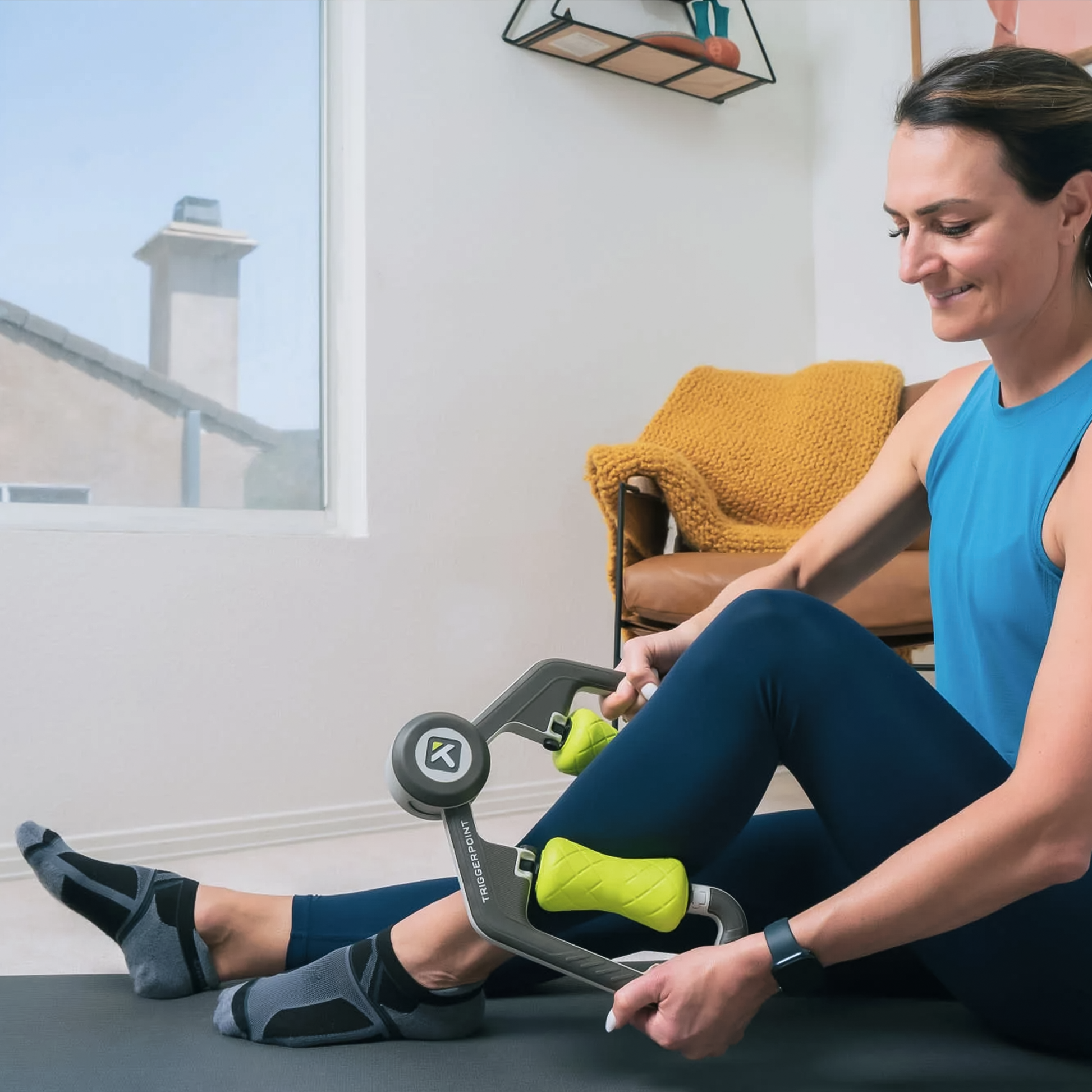 A woman using the TriggerPoint FUSE Massager on her legs, demonstrating its dual-muscle massage design for recovery.