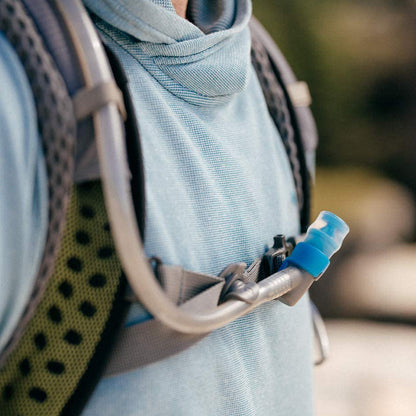 A man prepares for a hike, showcasing his hydration pack's bite valve.
