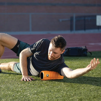A person using the TriggerPoint Grid Travel in orange to massage his arm muscles